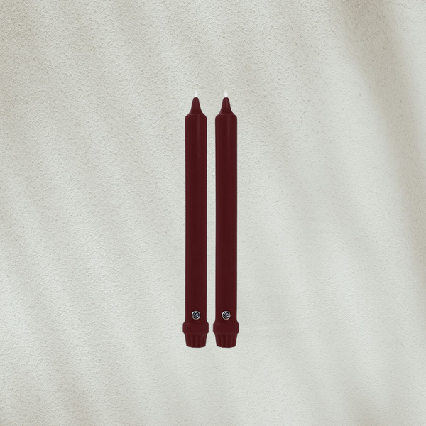 Two burgundy candles on a textured beige background