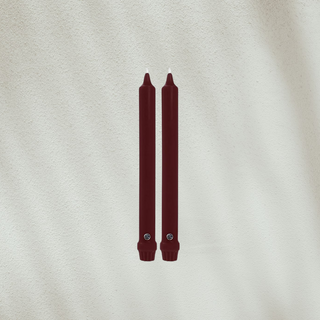 Two burgundy candles on a textured beige background