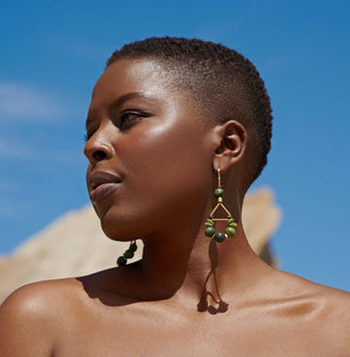 Woman wearing green earrings against a clear blue sky