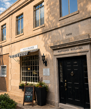 Stately building with 'Nest Proper' sign and black door, 'Maryland Building' plaque.