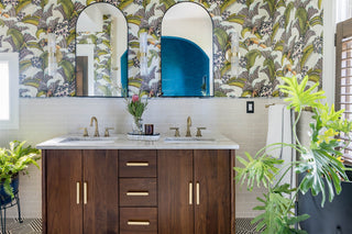 Bathroom with wooden vanity, floral wallpaper, and plants