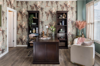 Home office with floral wallpaper, wooden desk, and decorative elements.