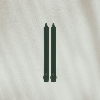 Two green candles on a textured beige background